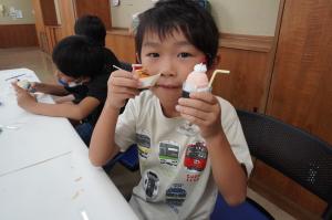 たこやきとクリームソーダを持った子どもの写真